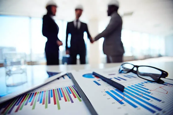Business professionals shaking hands over project charts