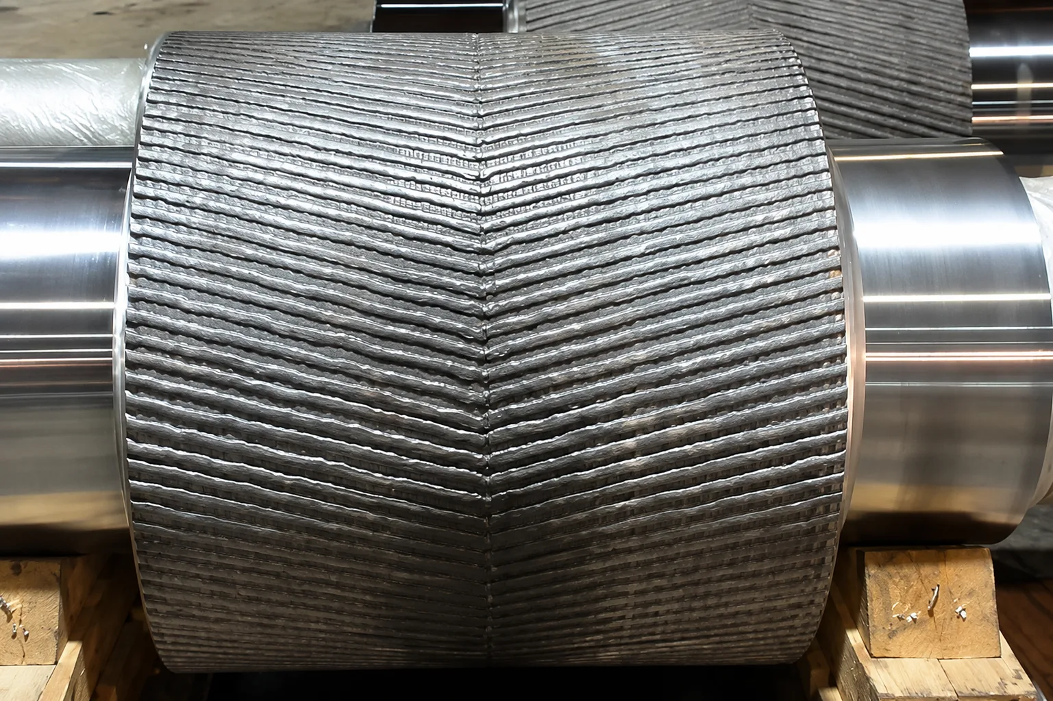 Large roll with chevron hard-facing pattern between machined bearing surfaces
