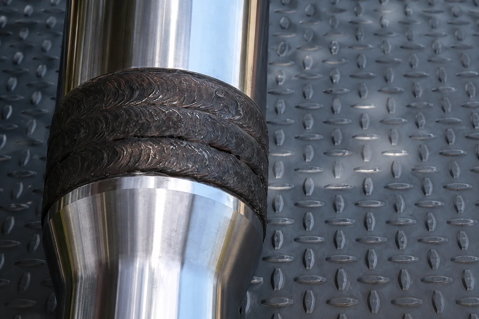 Finished cylindrical part with hard-facing weld layers and machined shiny surfaces
