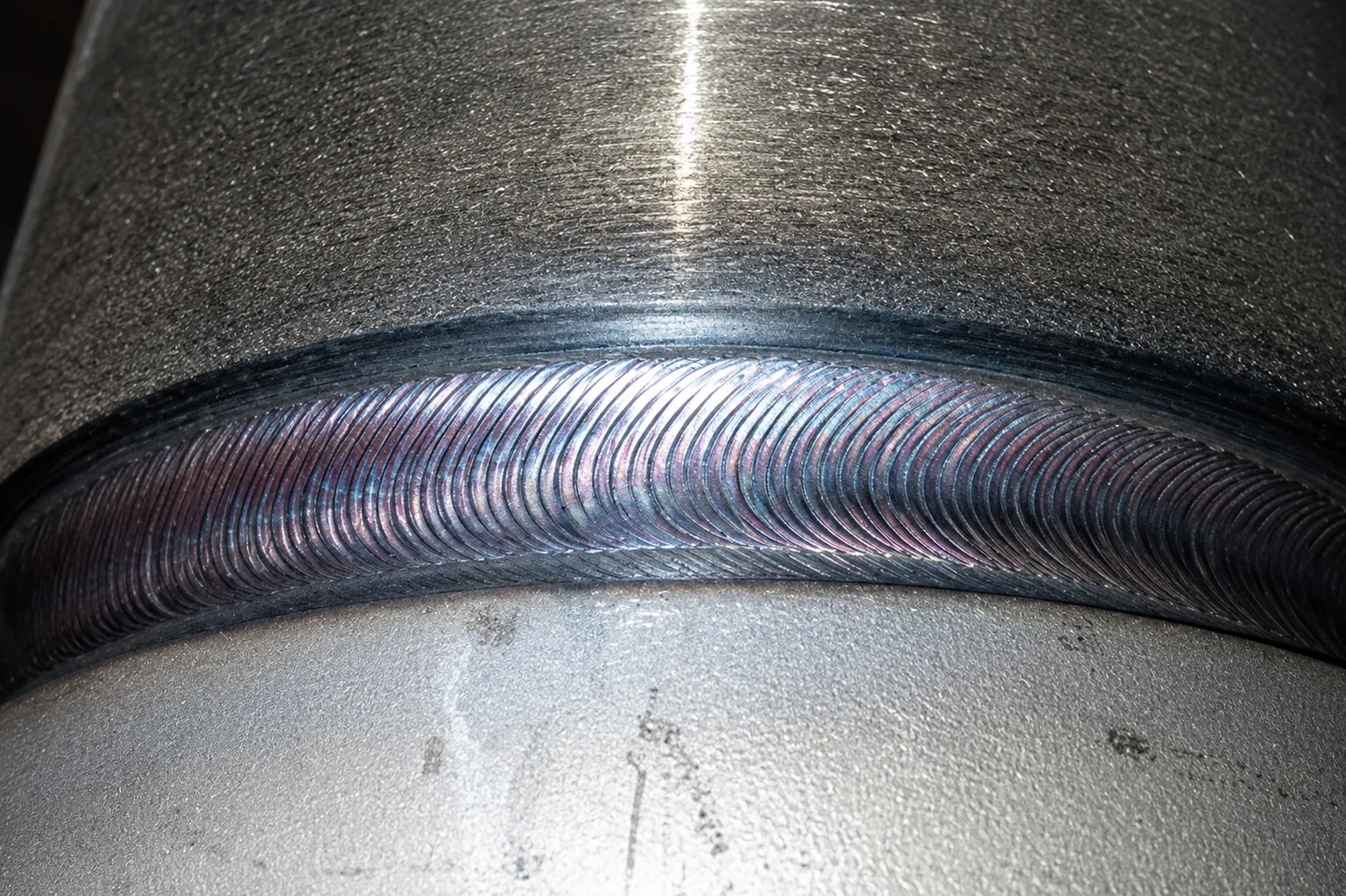 Close-up of a uniform hard-facing weld bead on a curved metal surface