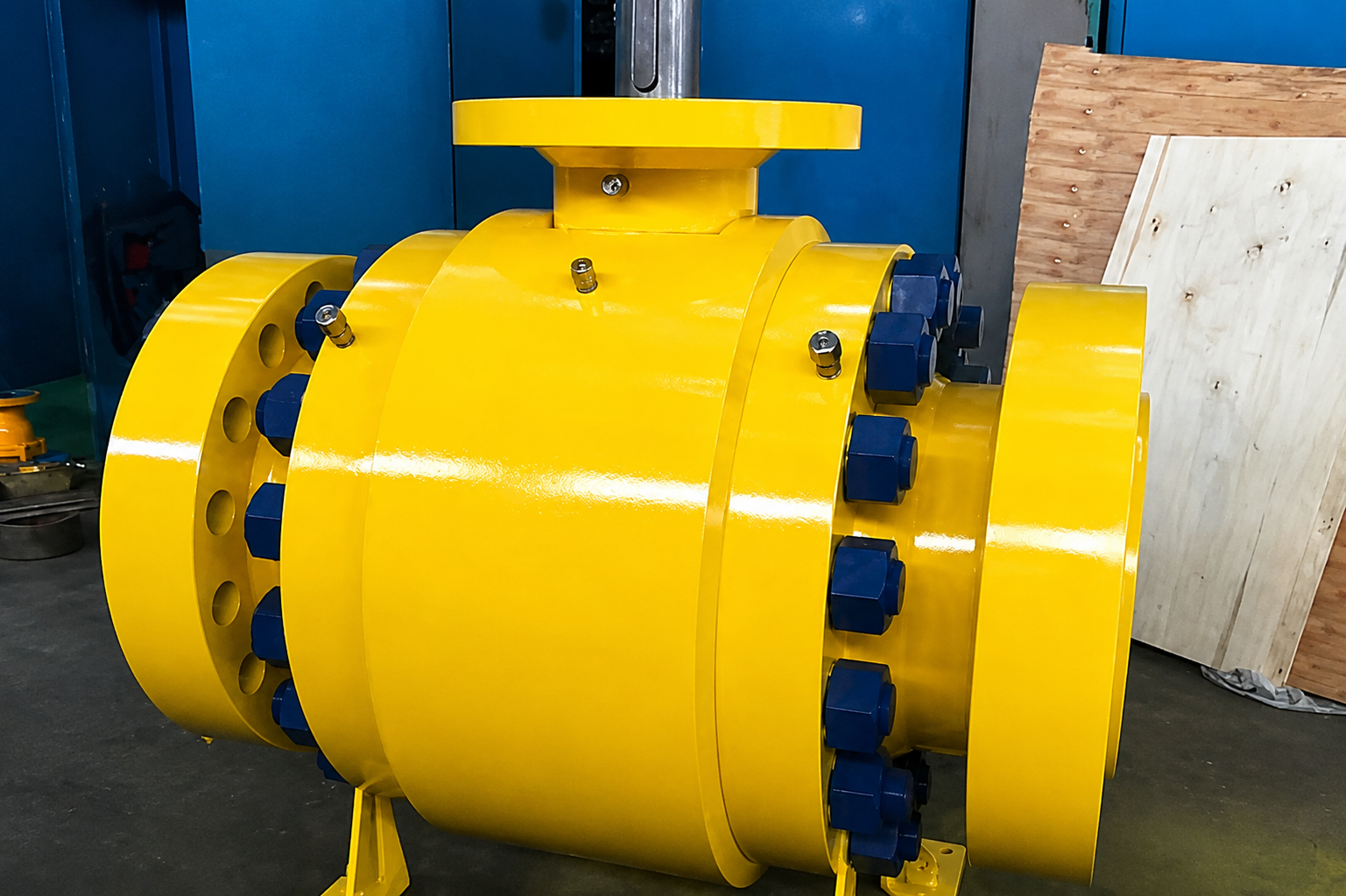 Yellow mechanical valve assembly with blue fasteners in the workshop