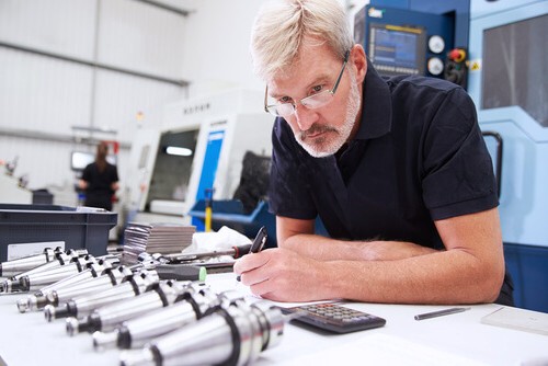 Inspector documenting finished cylindrical components in a workshop