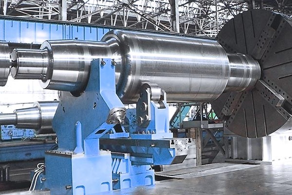 Large rolling mill roll mounted on a horizontal lathe for machining