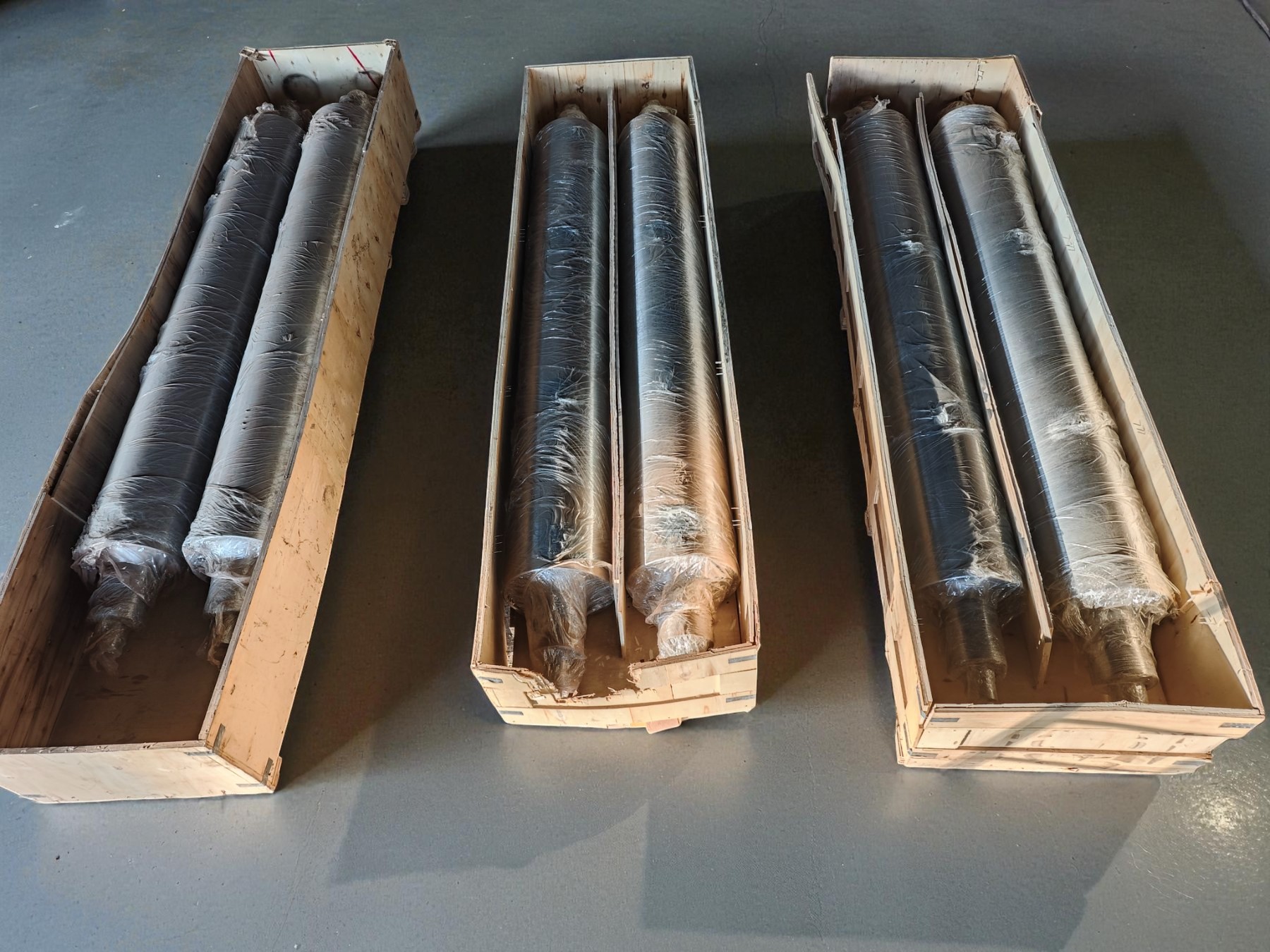 Six rolling mill rolls wrapped for protection in three wooden shipping crates