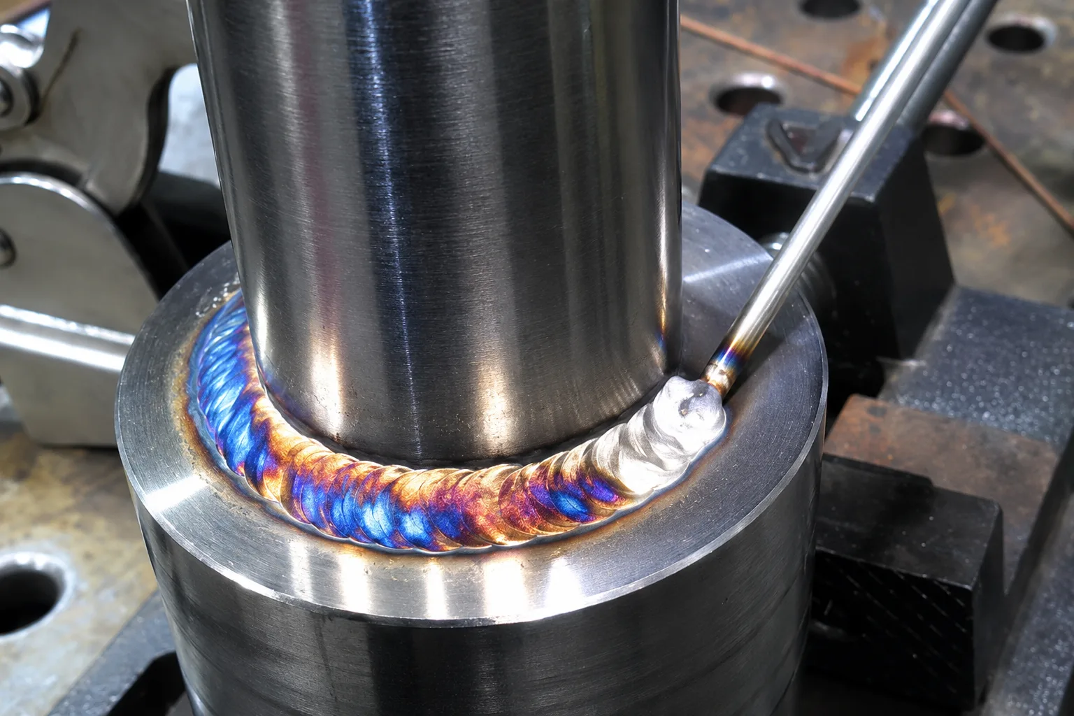 Close-up of TIG welding creating a clean colored bead around a cylindrical metal joint